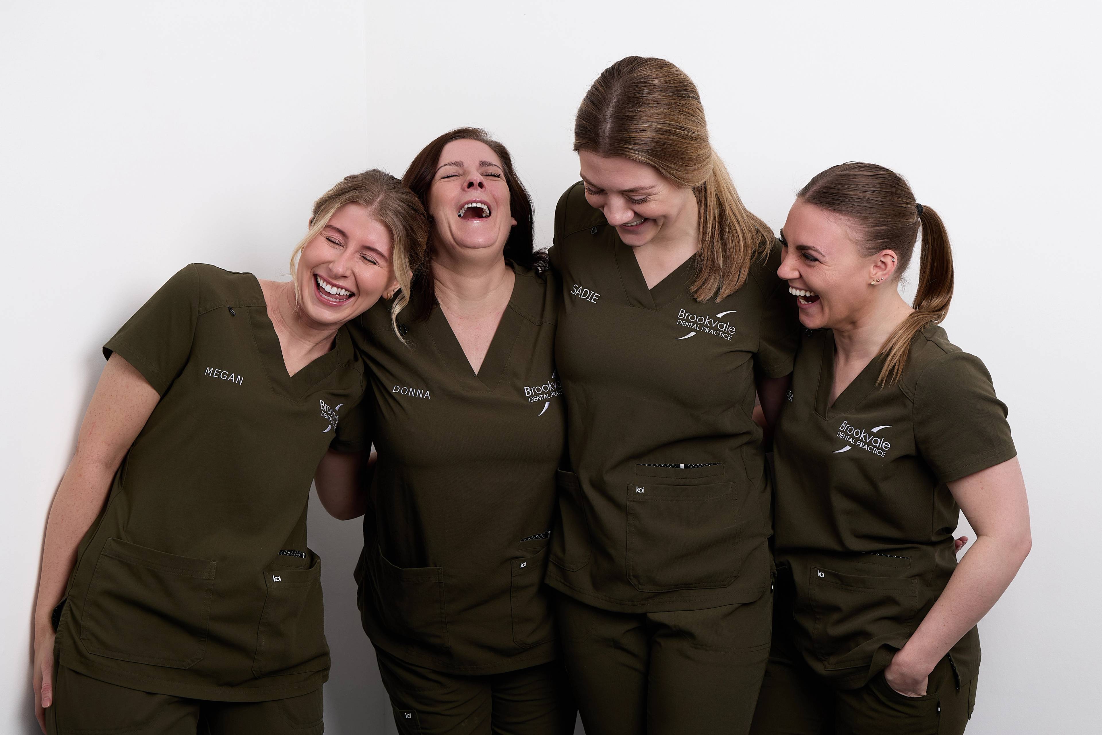 OUr dental nursing team laughing together in front of a white background