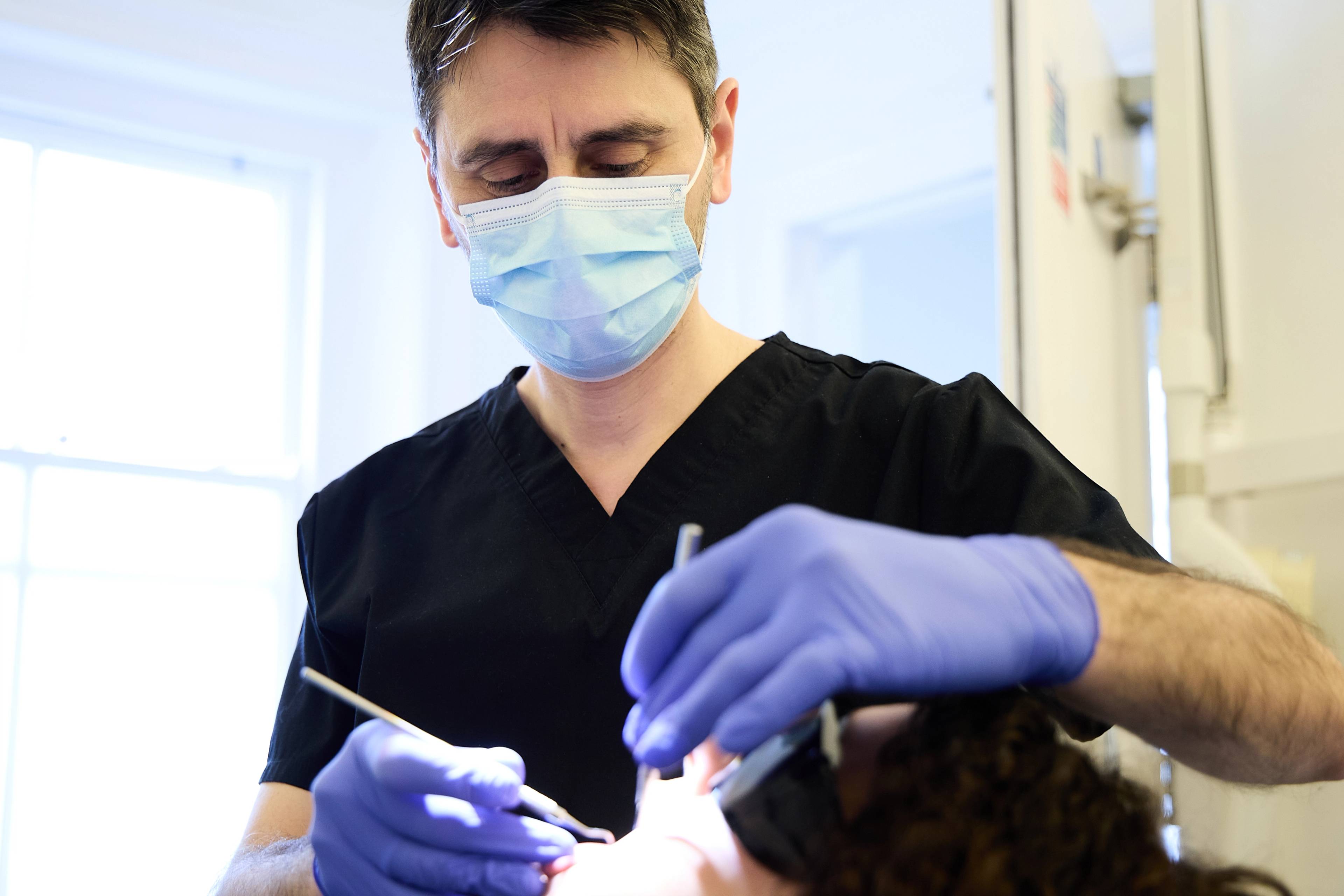 Oreste Gheorghe examining a patient's teeth
