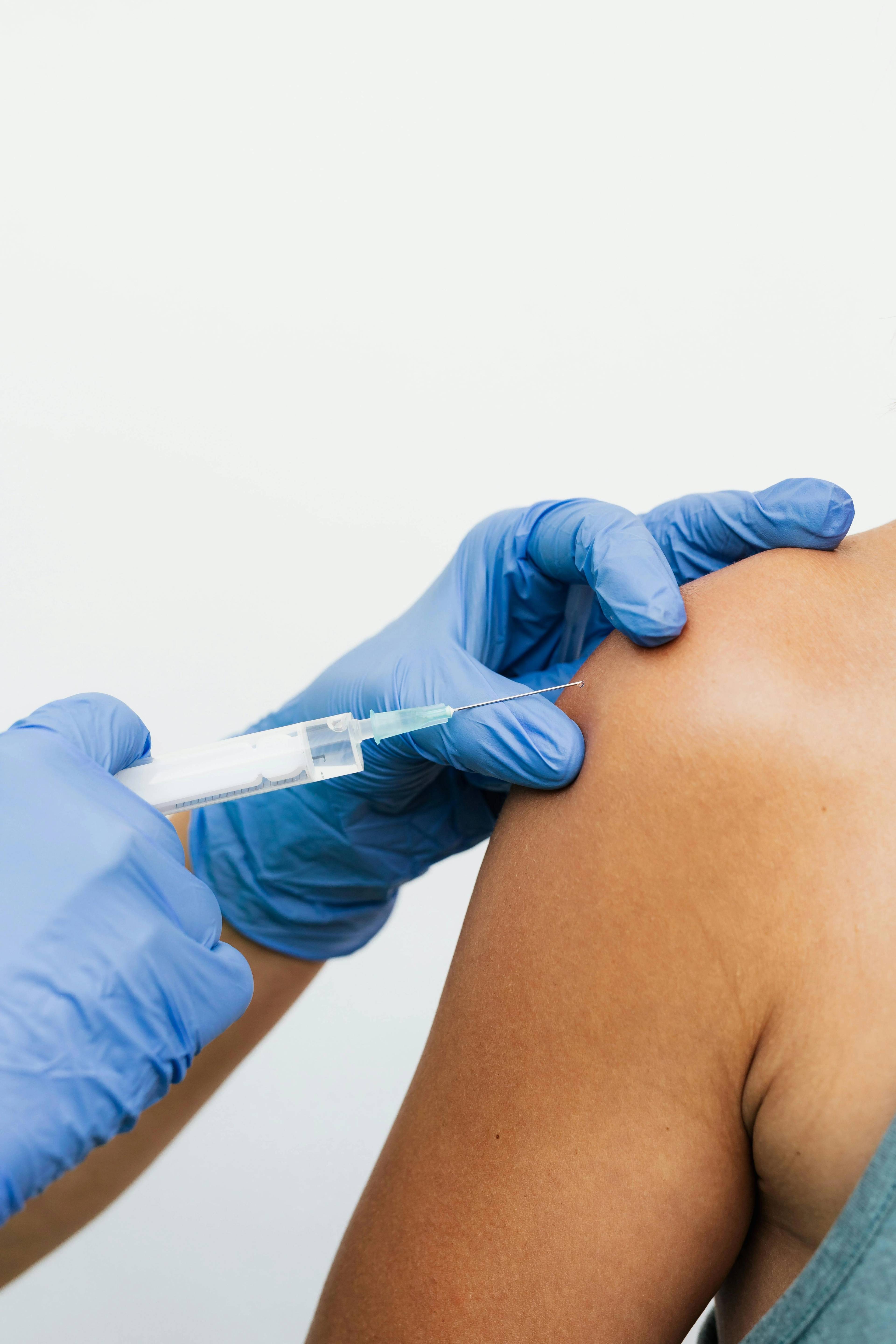 Stock photo of a woman receiving an injection in her shoulder