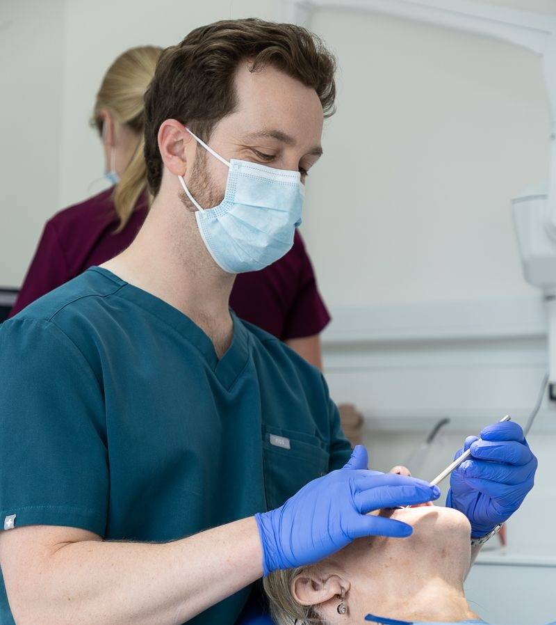 Tom Mann inspecting a patient's teeth