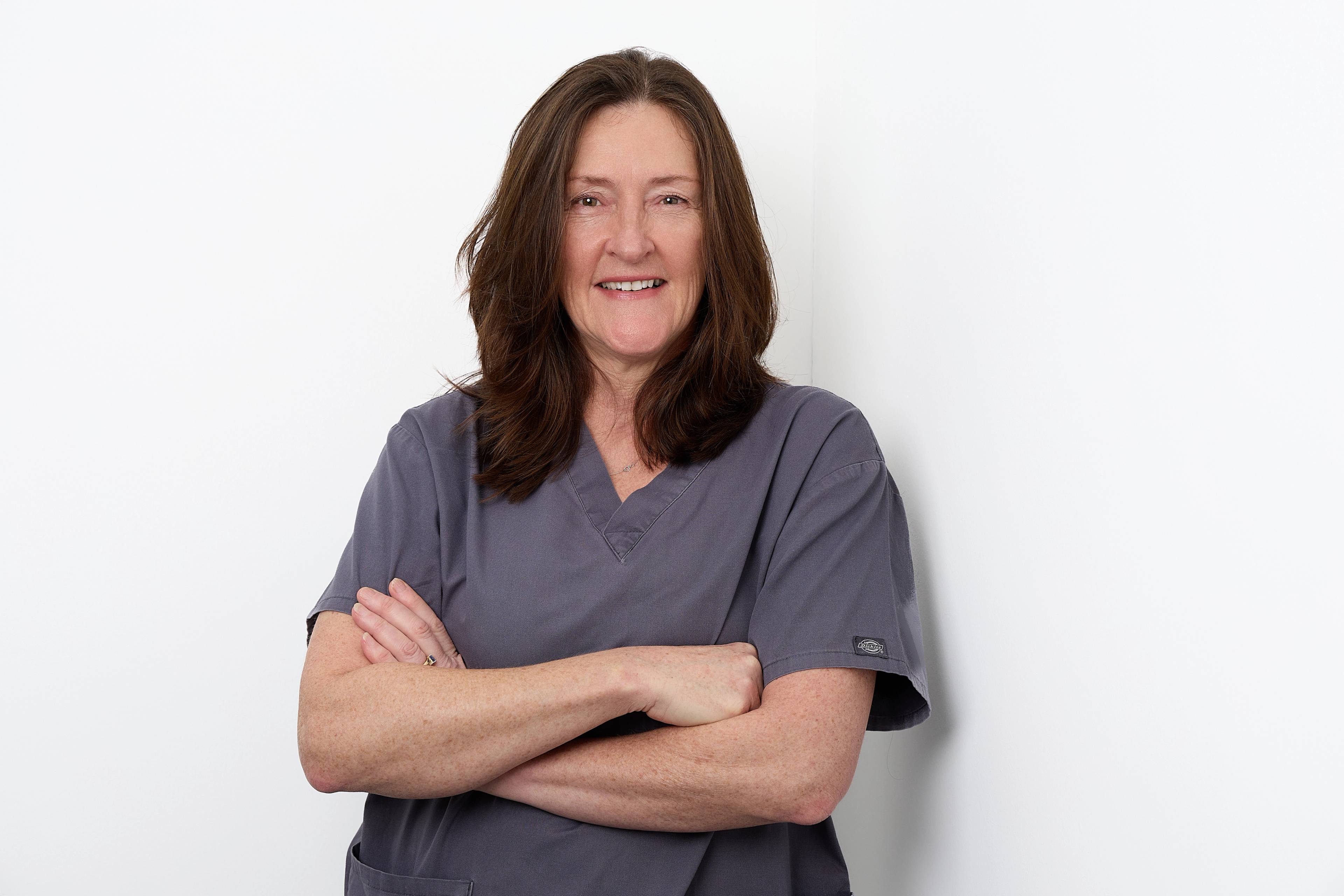 Rachel Pattern standing with her arms folded in front of a white background