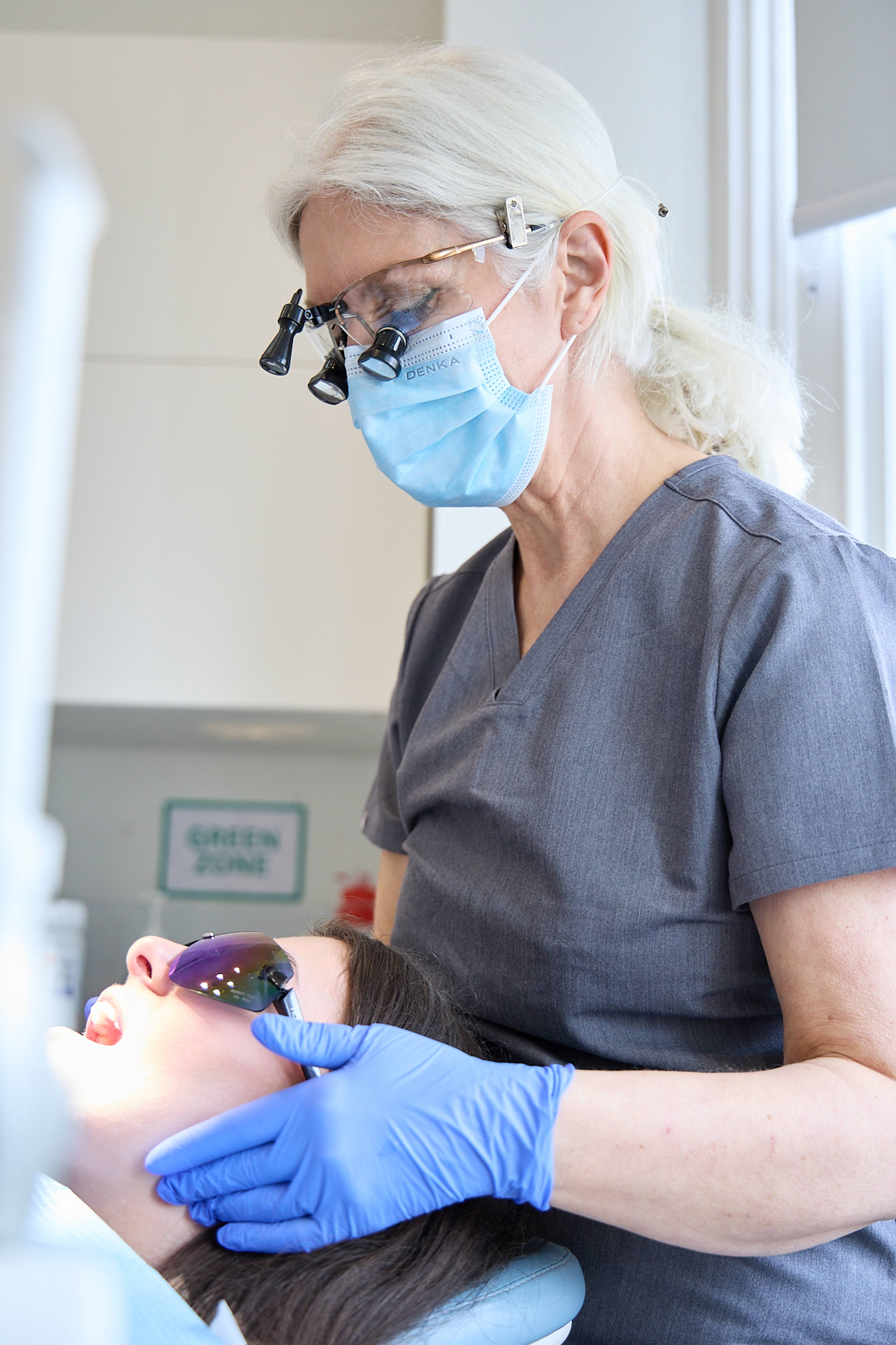 Cathy Barber inspecting a patient and wearing loupes