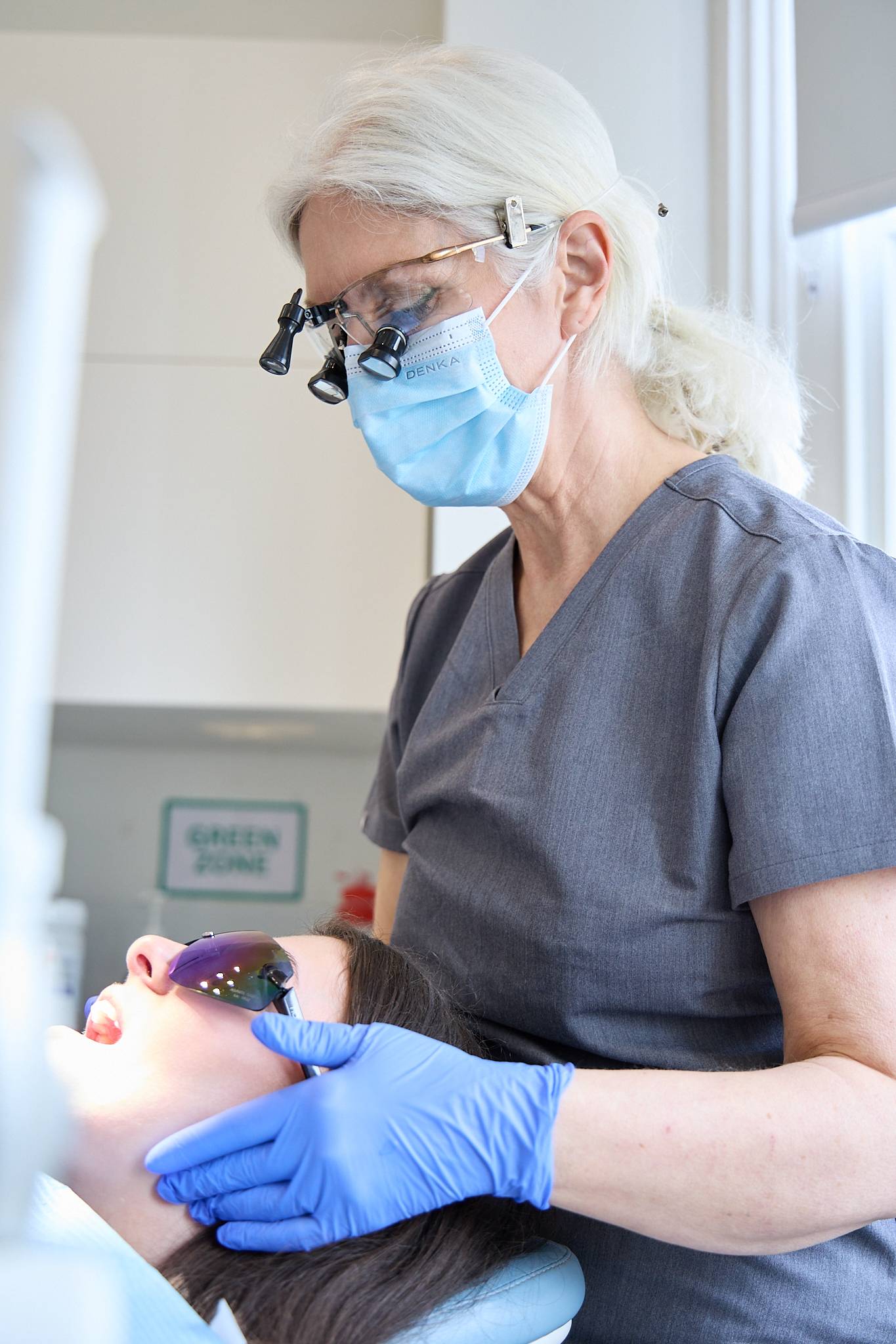 Cathy Barber inspecting a patient and wearing loupes