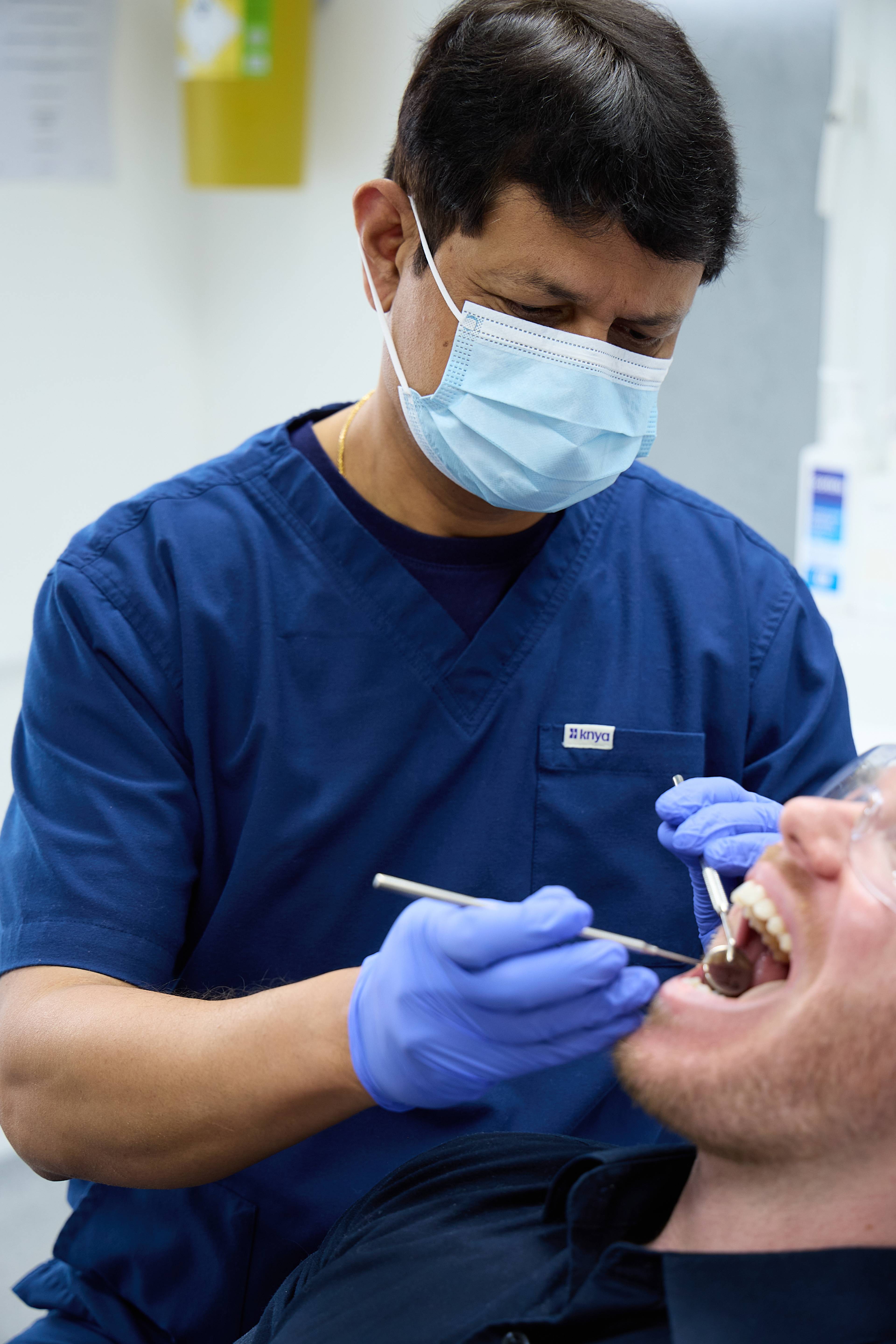 Dentist Rajesh Kumar inspects a patient's teeth