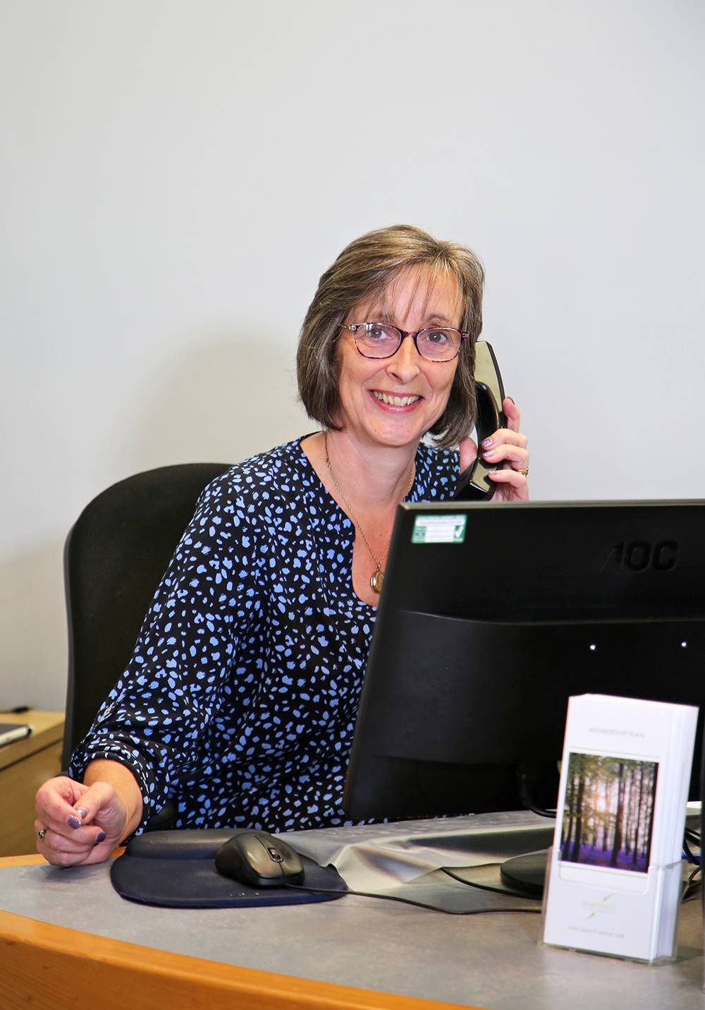 The receptionist at Merrifield dental practice smiling while speaking on the phone