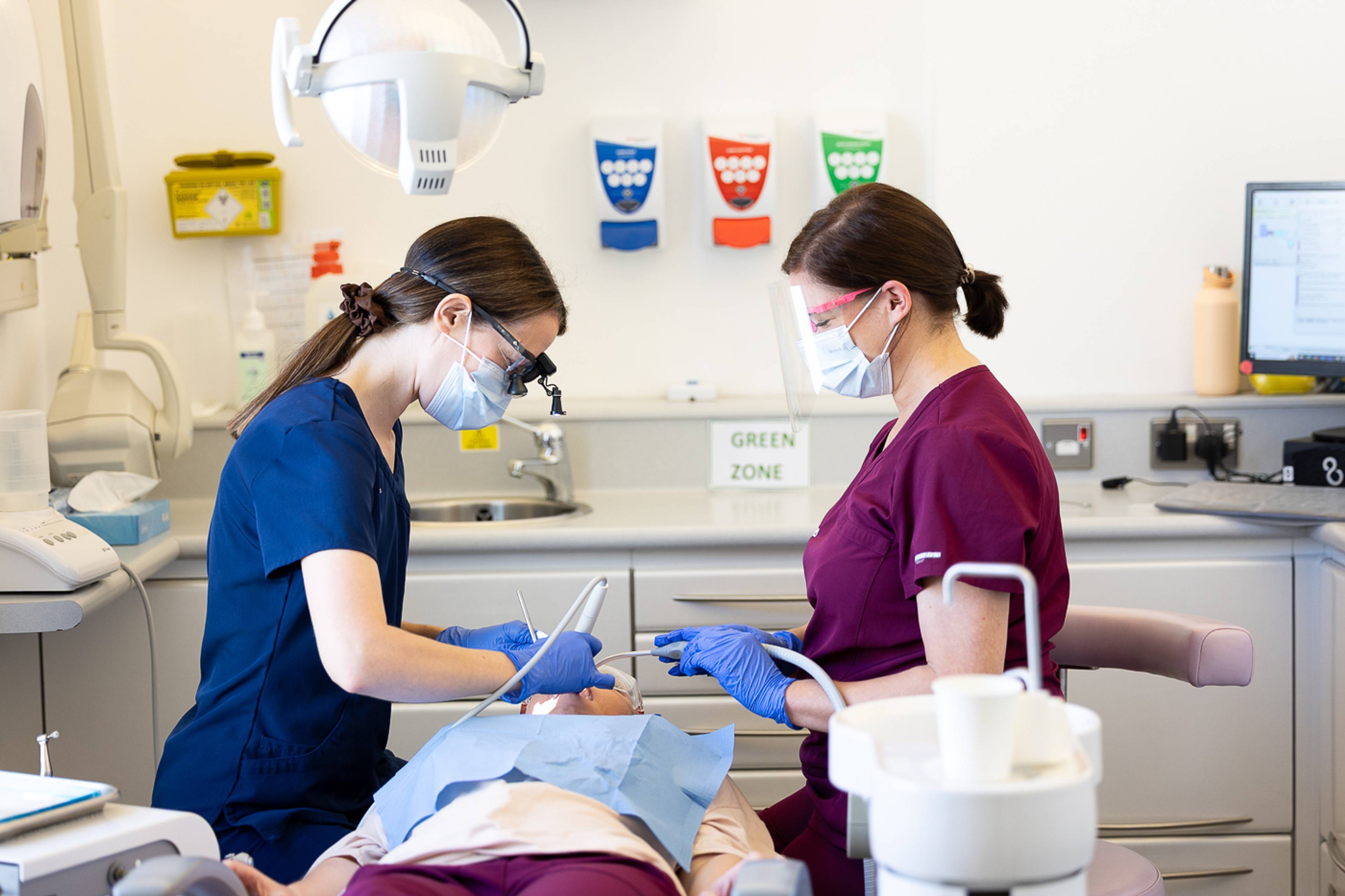 A dental hygienist and a dental nurse working on a patient