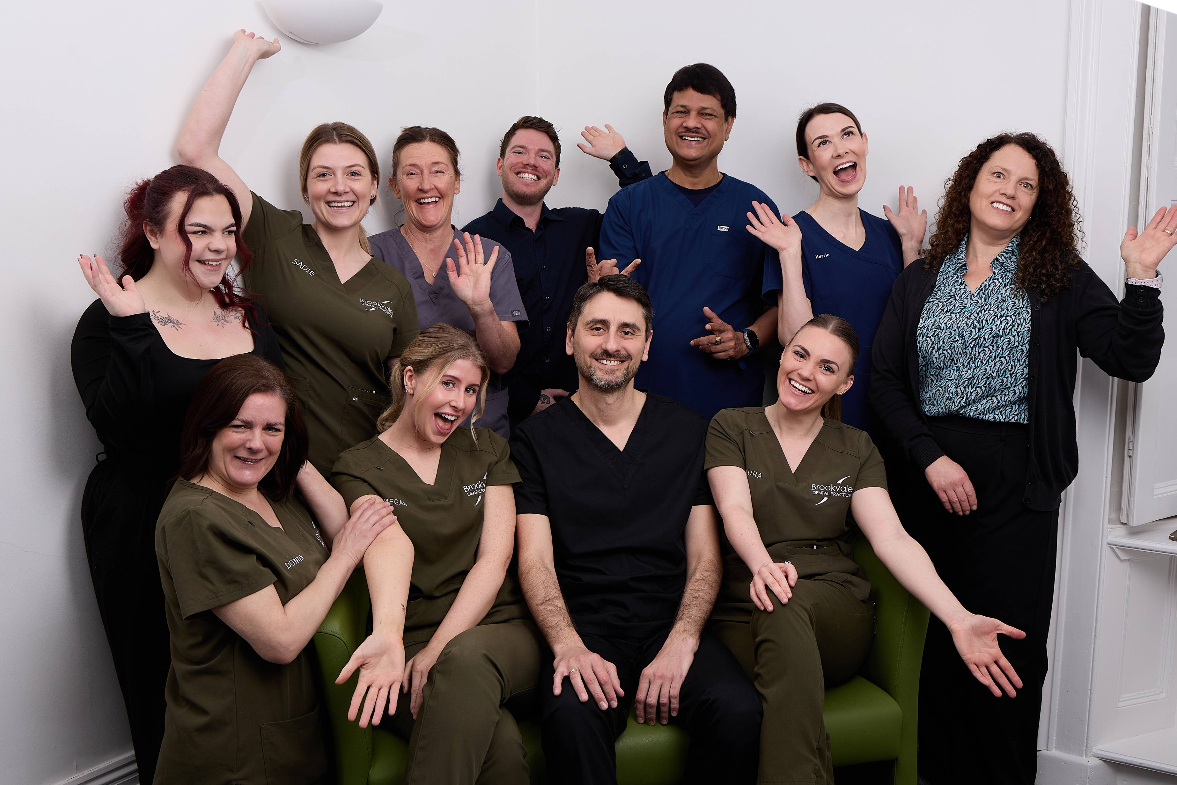 The team all smiling with their hands out while sitting on or around a green sofa with Oreste Gheorghe in the middle