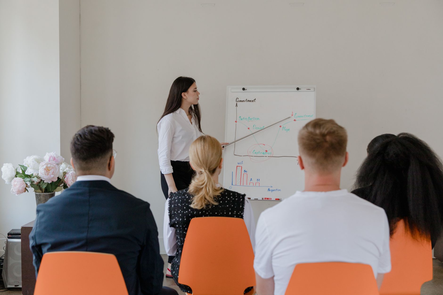 A professional conducts a presentation in an office setting to a diverse team.