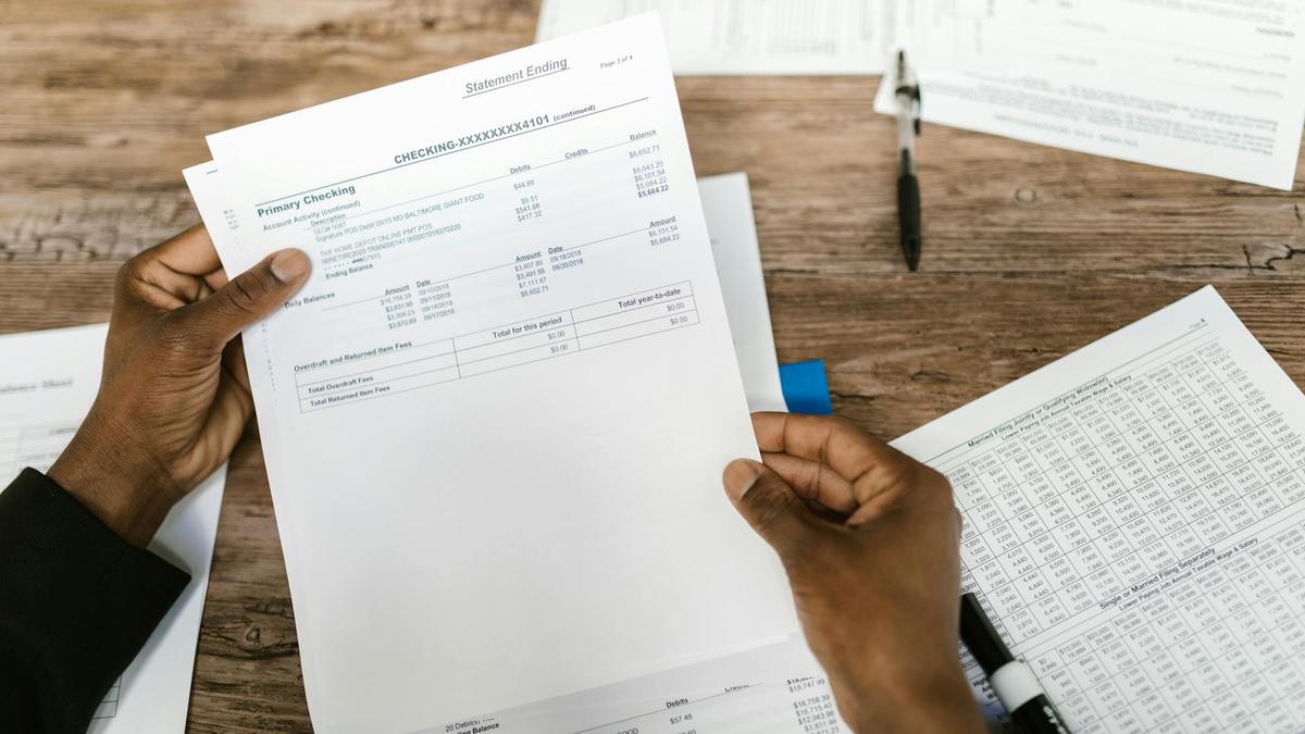 Hands holding financial papers for tax preparation and analysis.
