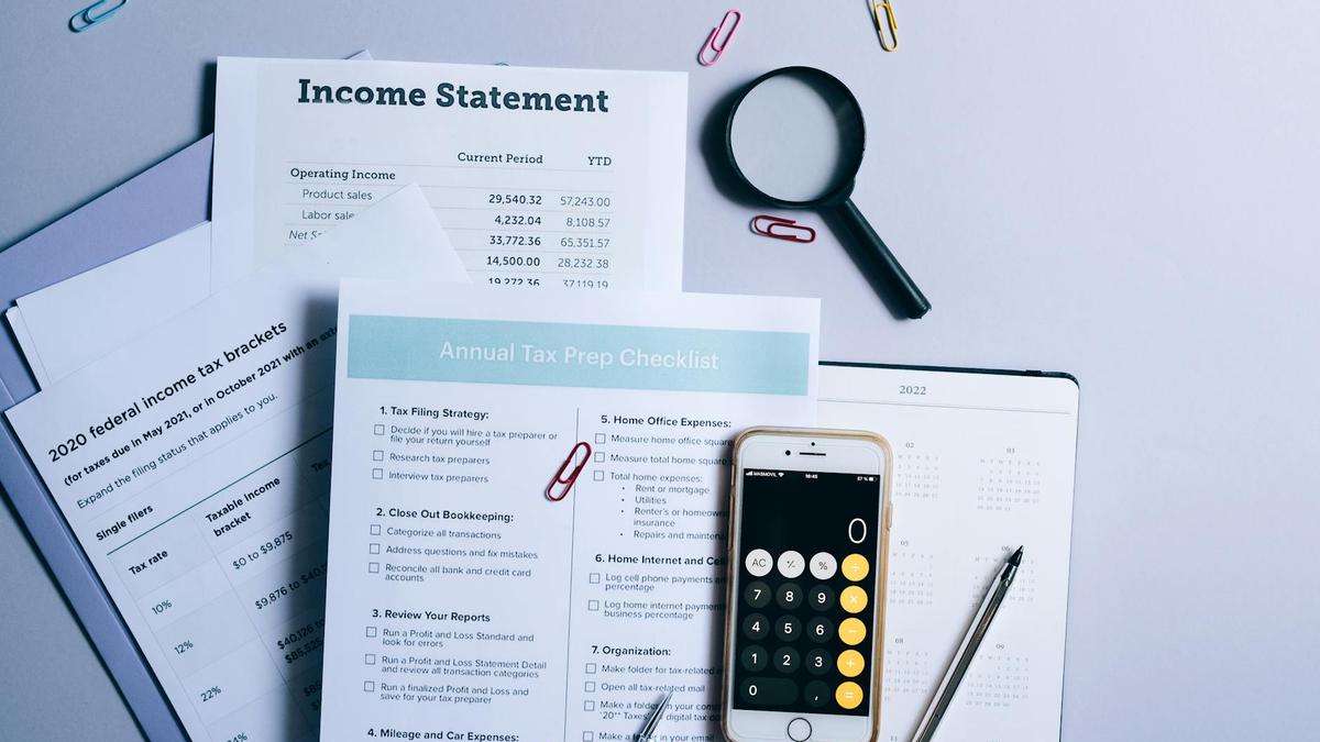 An organized desk with tax documents, checklist, and gadgets for tax preparation.