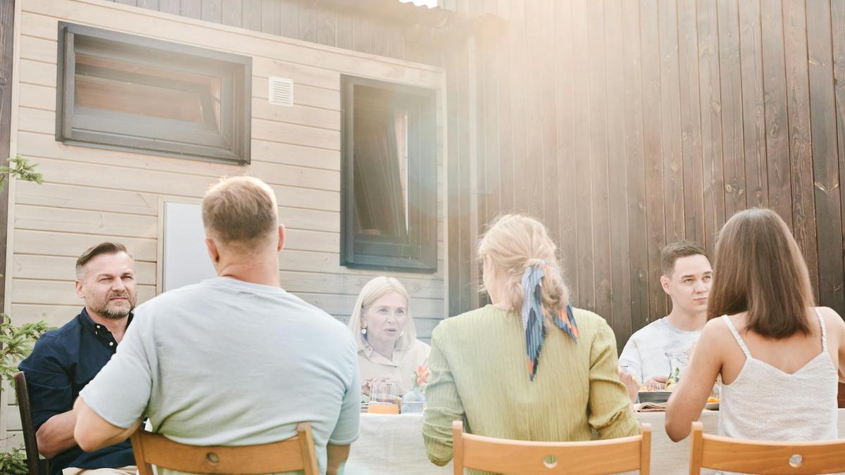 A family enjoying an outdoor meal together in a sunny backyard setting.