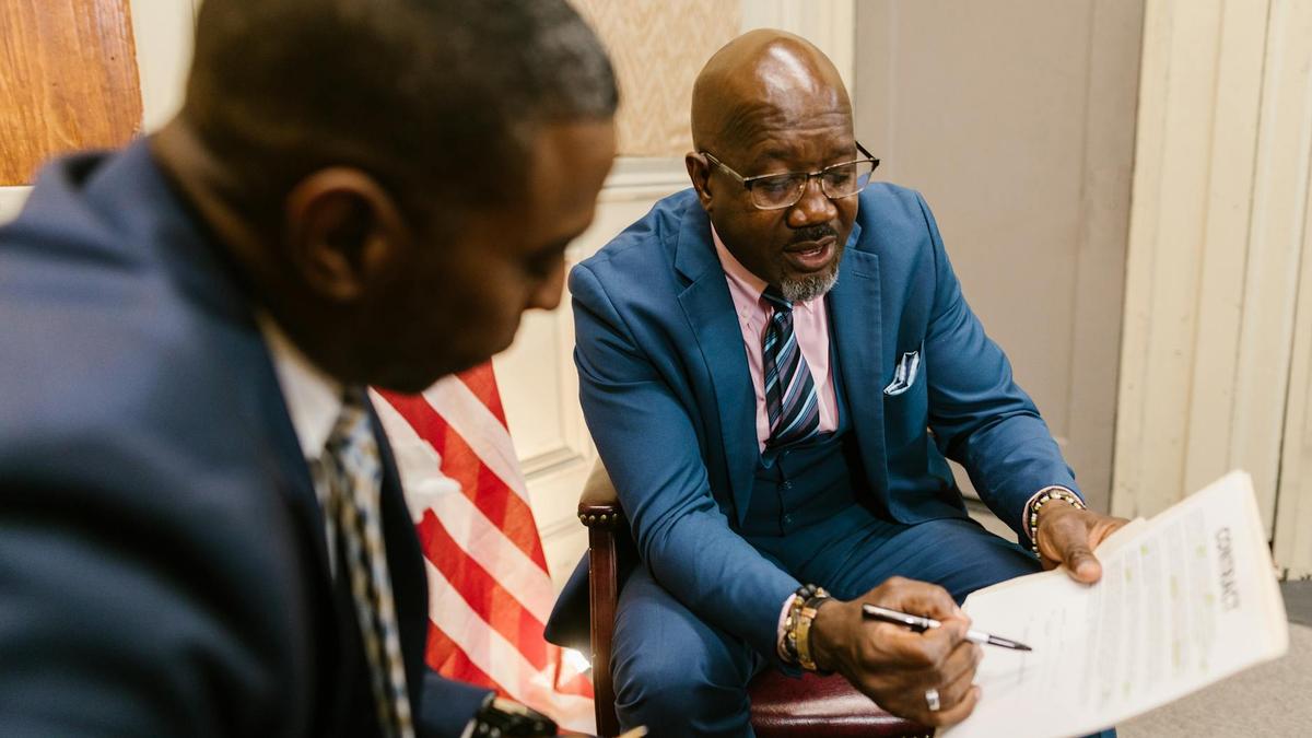 Two businessmen reviewing a contract document in an office setting.