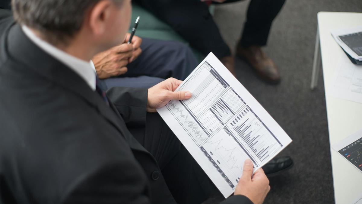 Two businessmen analyze financial documents during a meeting, focusing on data trends and performance.