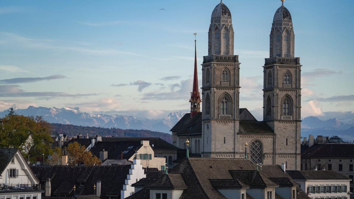 Capture of Grossmünster Church with Swiss Alps in Zurich during daytime.