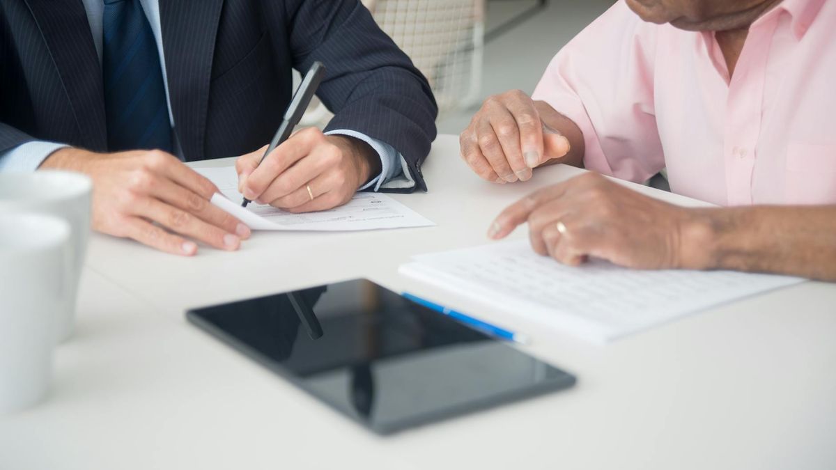 Two professionals discussing and signing documents in a business meeting.