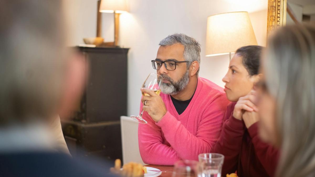 A group of friends shares wine and conversation during a cozy dinner indoors in Portugal.
