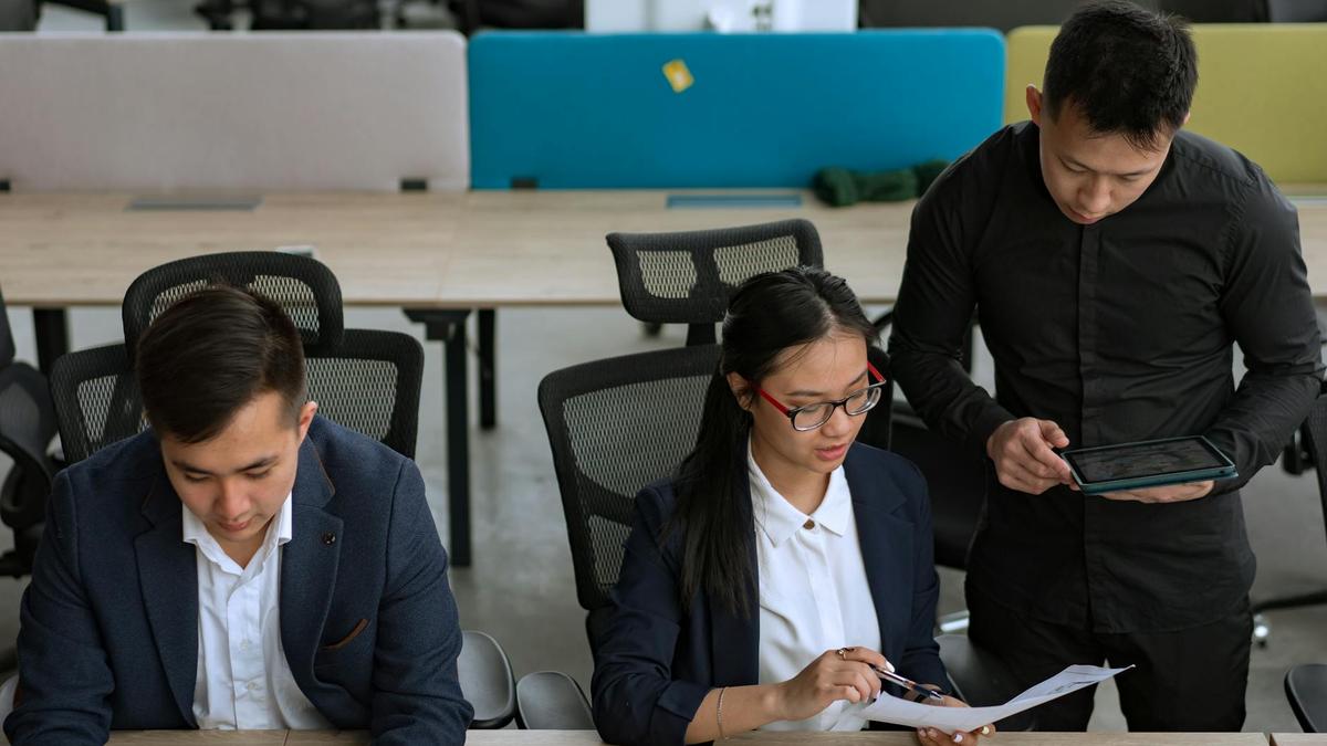 A professional team collaborating in a modern office setting, focusing on documents and technology.