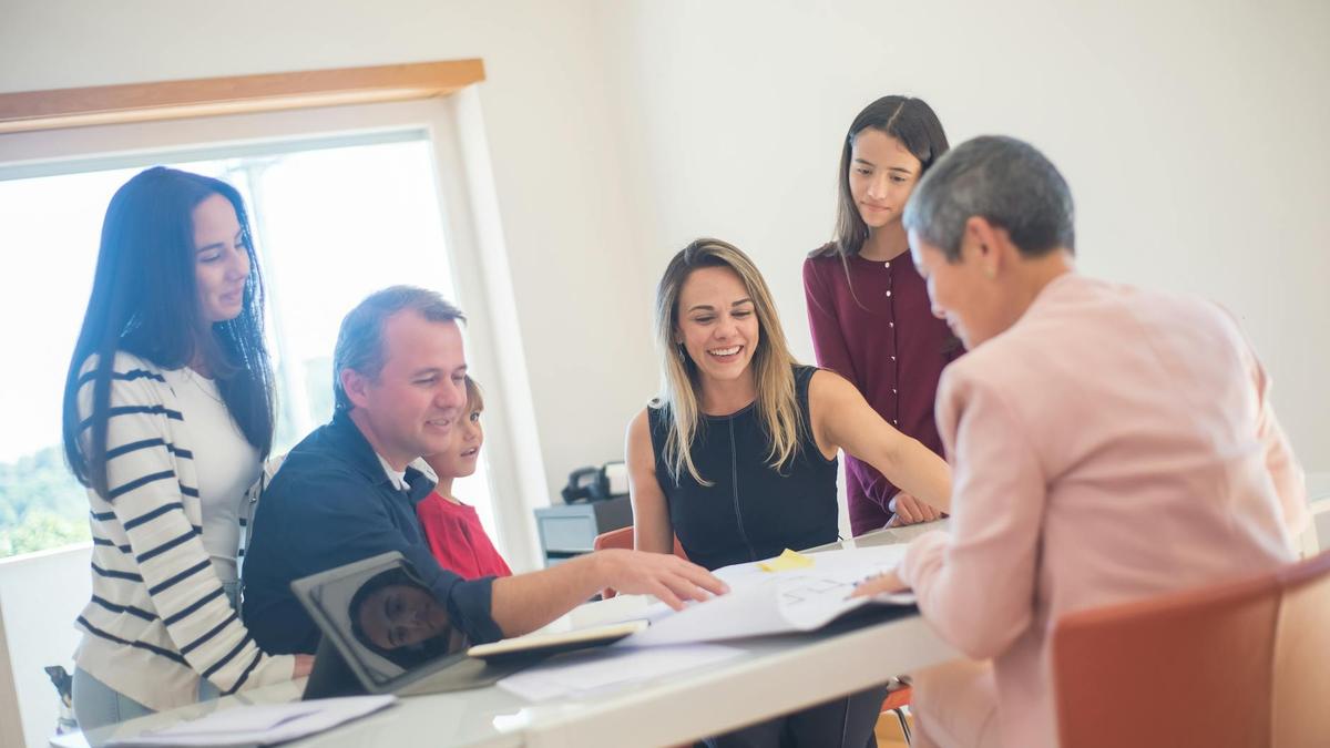 A happy family gathering around a desk during a home meeting, discussing documents.