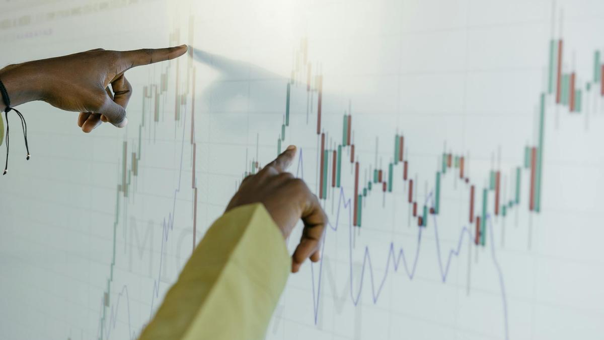 Hands pointing at a financial stock chart on a digital screen, highlighting data analysis and trends.