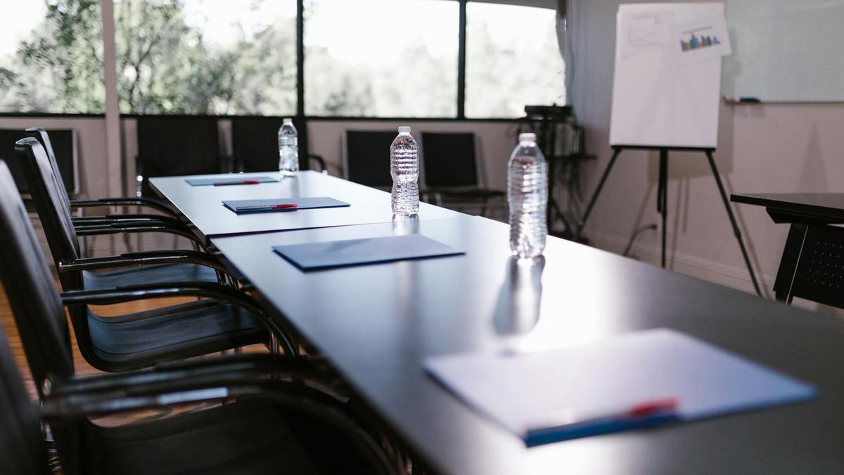 Spacious conference room with water bottles and notes on a wooden table ready for a meeting.