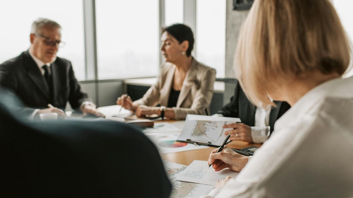 Colleagues discussing documents in a corporate office meeting.