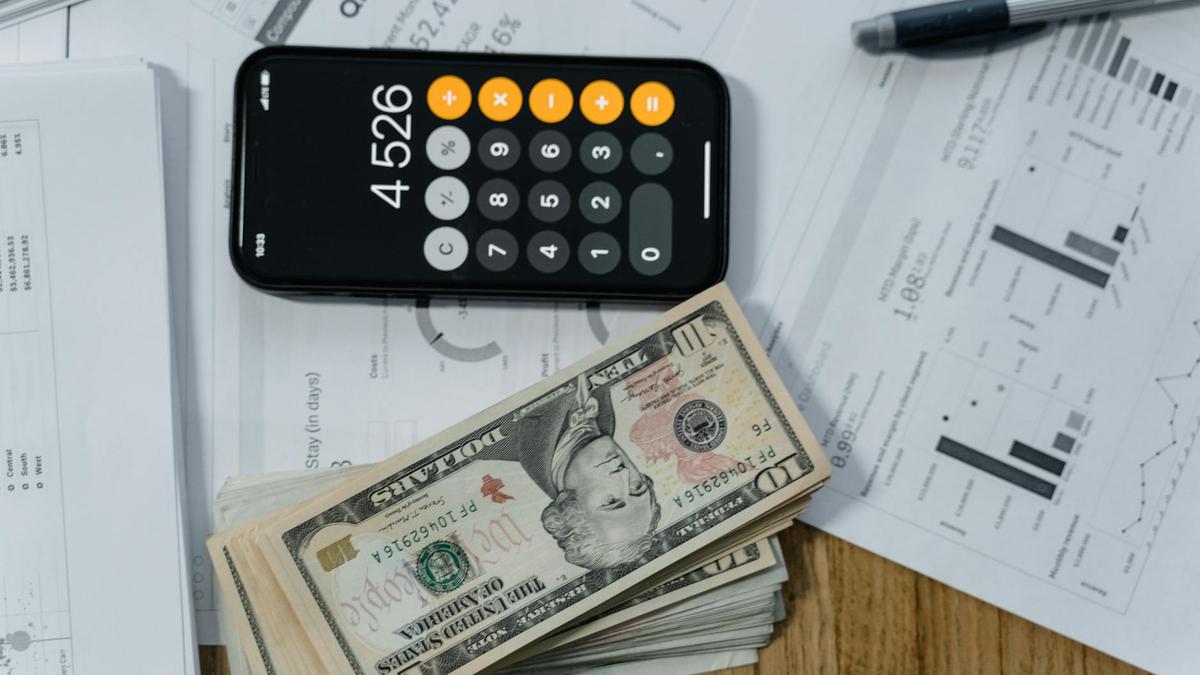 Mobile calculator, cash, and financial documents on a desk, indicating business planning.