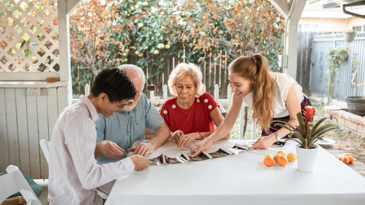 A happy family gathered around a table, sharing memories while looking at photos.