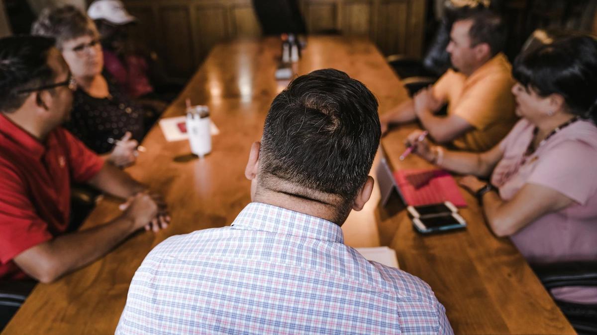 A business meeting with a diverse team discussing around a wooden table in an office setting.
