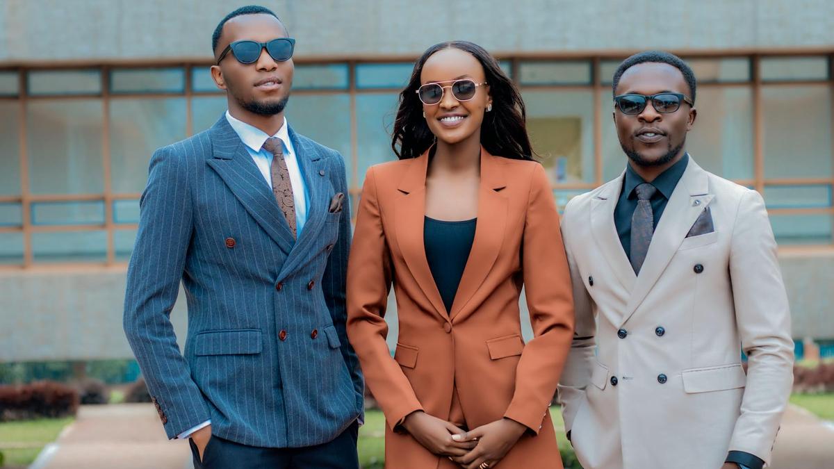 Three young professionals in stylish suits posing confidently outdoors.