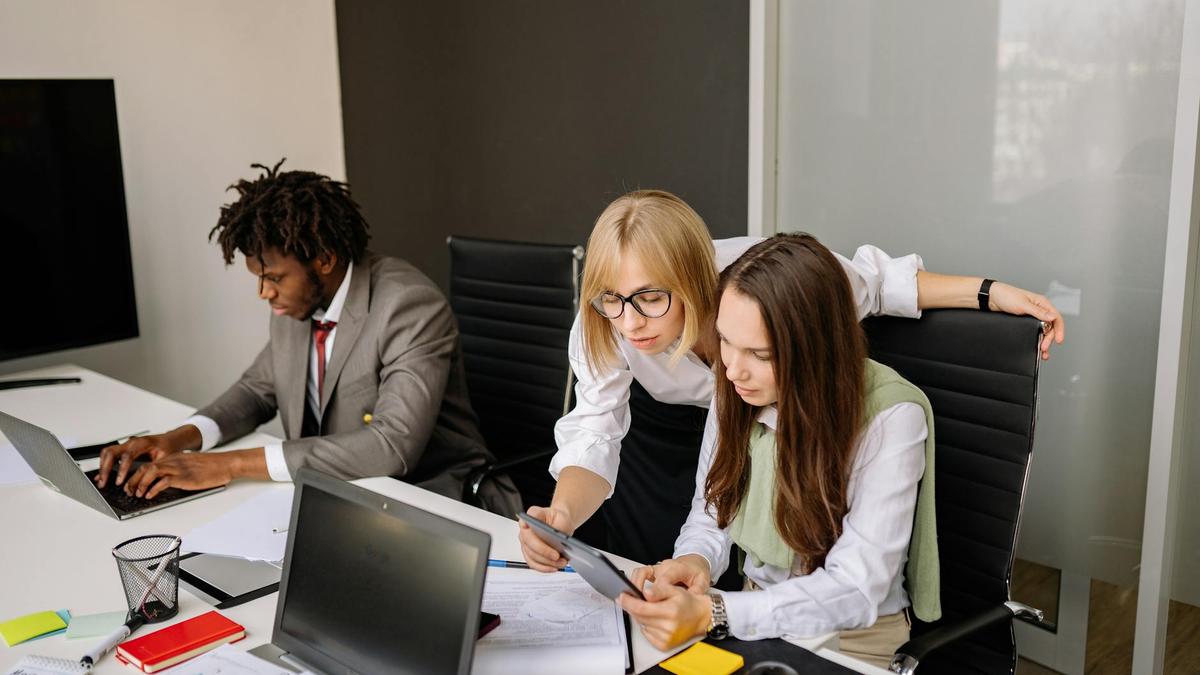 Business team collaborating in a modern office setting with laptops and tablets.