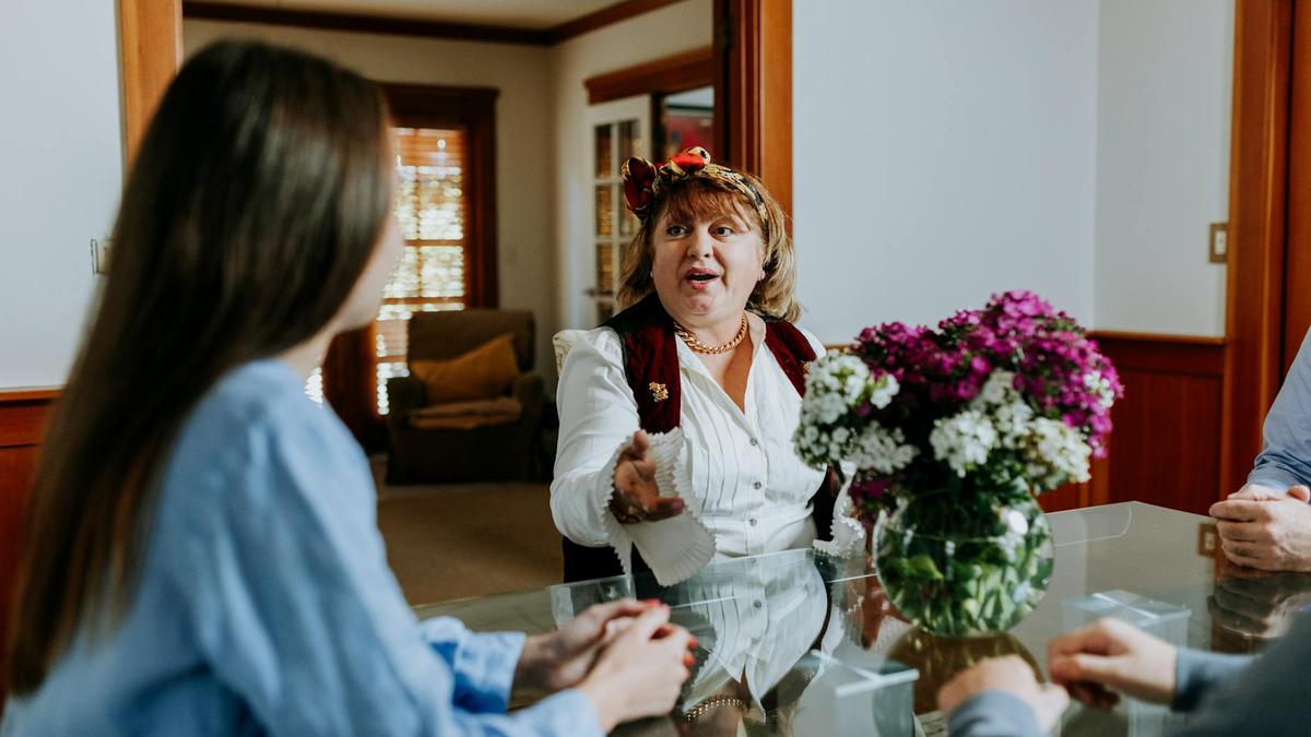 Joyful conversation during a family gathering indoors with a floral centerpiece on a glass table.