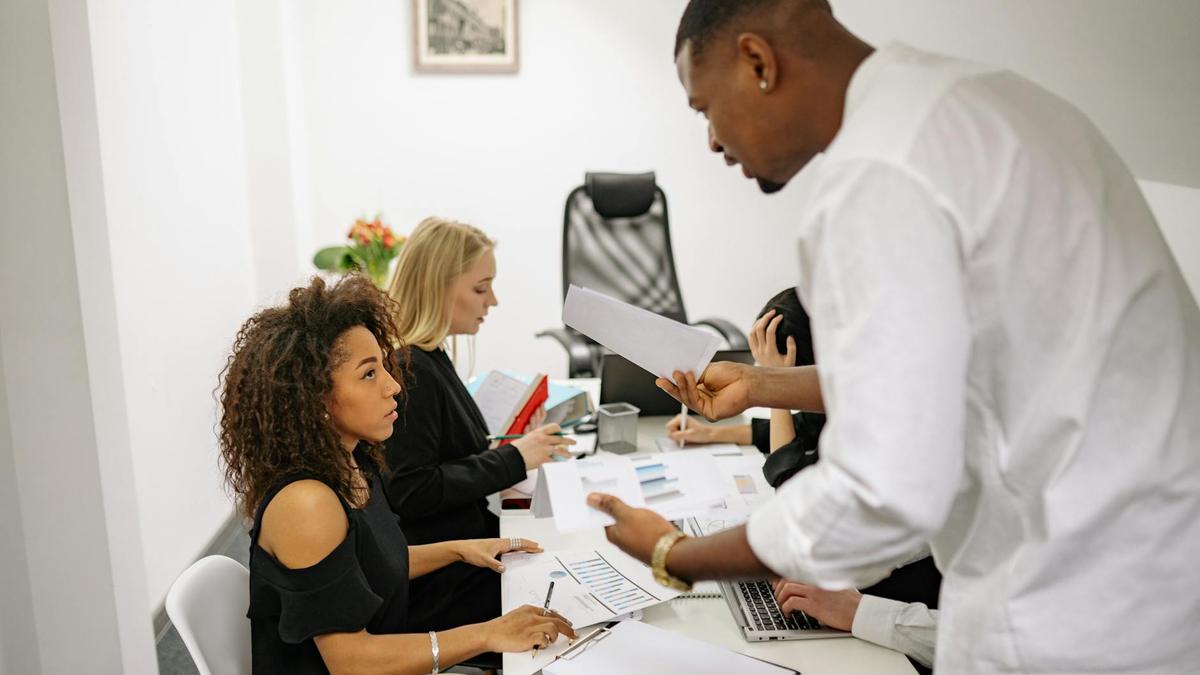 An office meeting where a man argues with a woman over documents, causing tension.