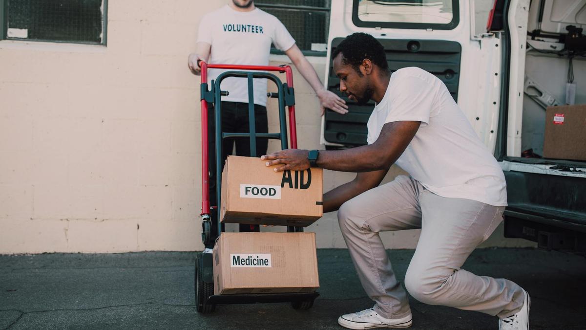 Volunteers organizing and loading boxes of aid, food, and medicine for donation.