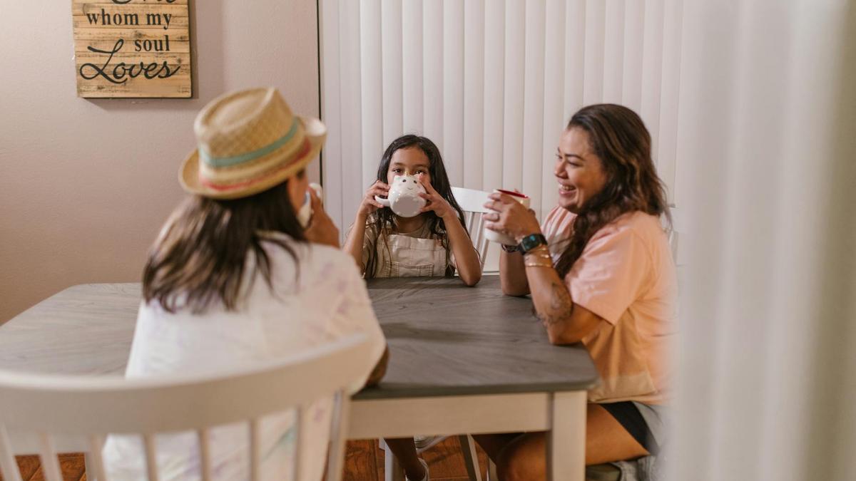 A joyful family gathering for tea around a cozy table, sharing smiles indoors.