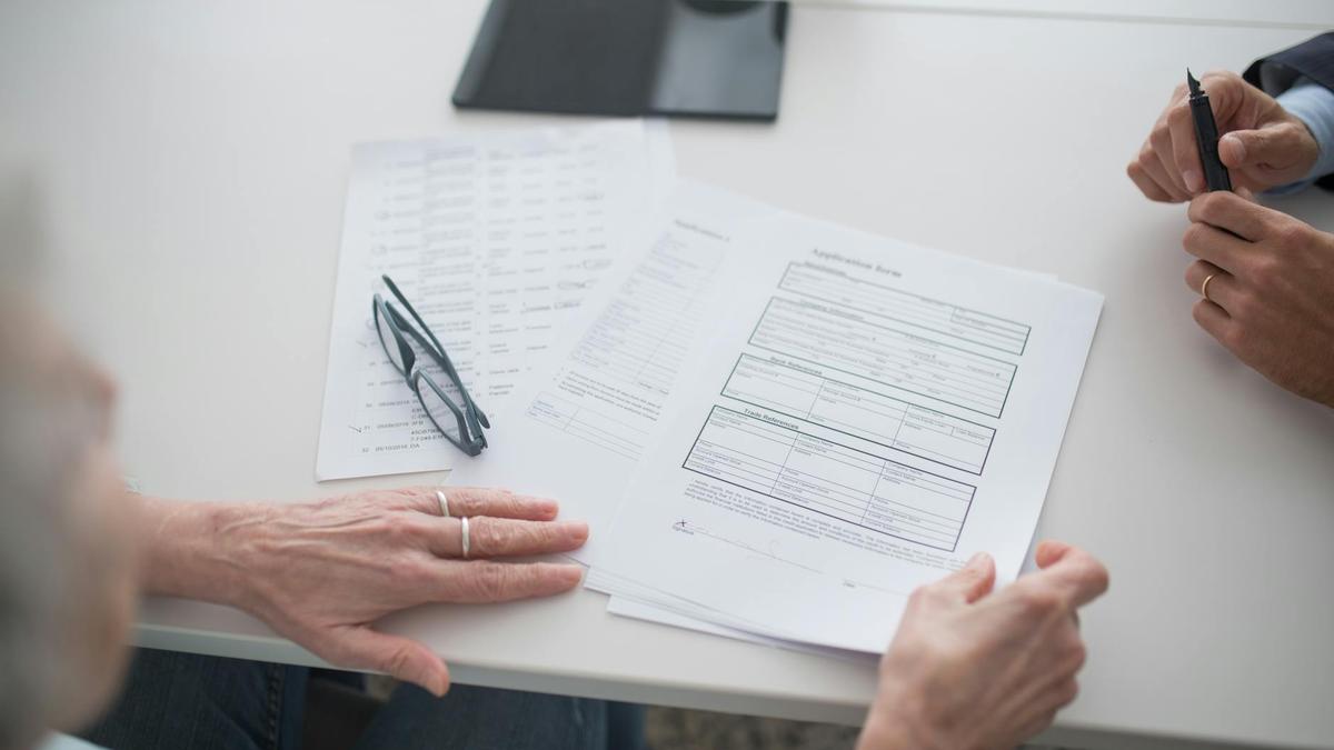 Close-up view of two individuals reviewing documents and forms in an office setting.