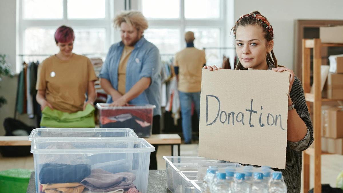 Group of volunteers organizing clothing and water donations indoors.