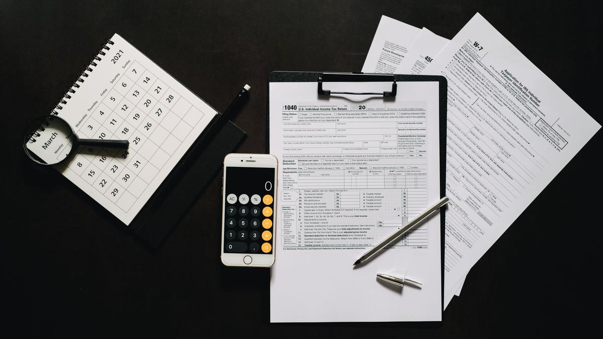 Flat lay of financial tools for tax preparation including forms, calculator, and calendar.