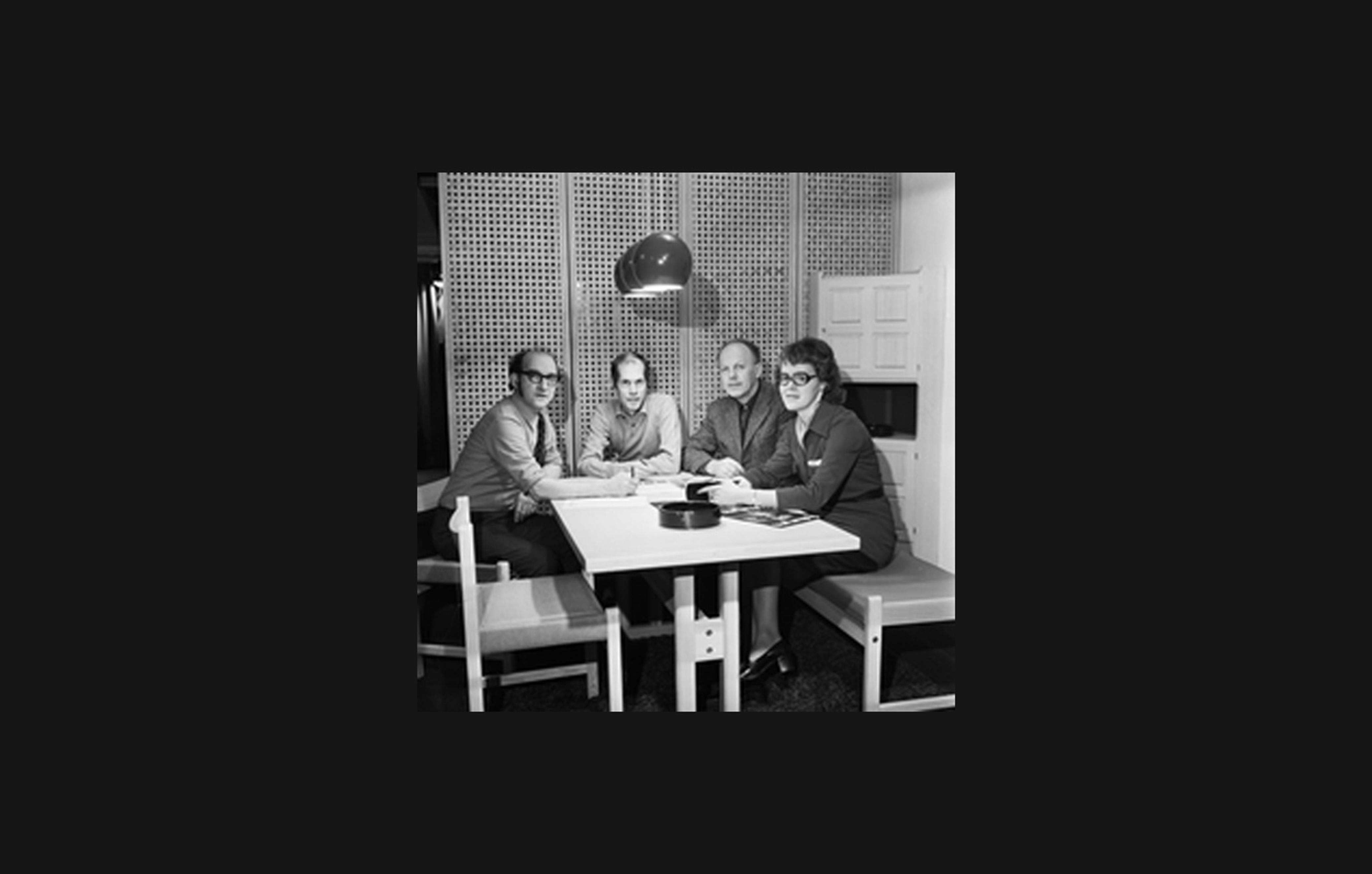 Rastad & Relling seated around a table under a pendant lamp, in an archive photo
