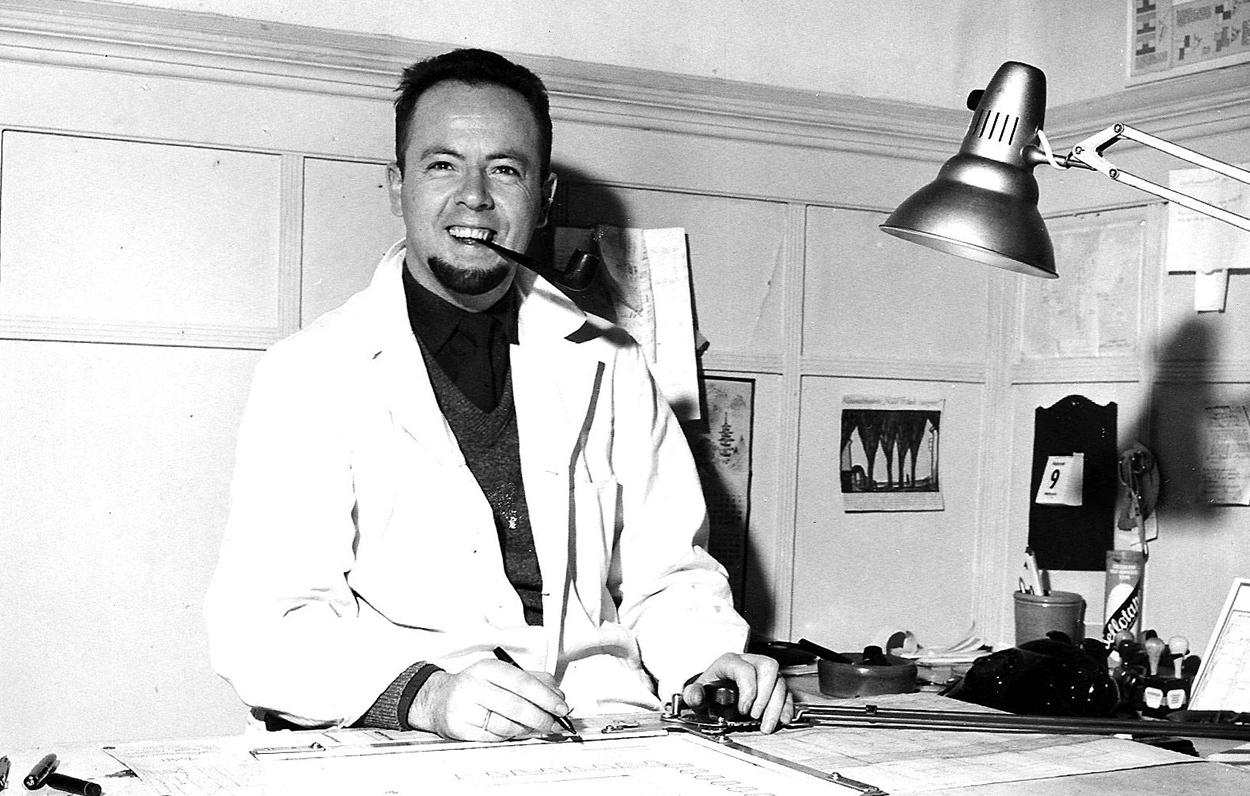 Hans Brattrud at his drawing table with a pipe, in an archive photo