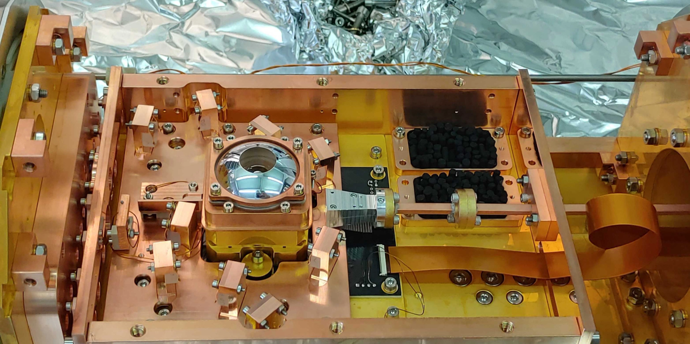 The experimental setup of the ETH researchers. The trap chip is located inside the container underneath the silver cupola, in which a lens captures the light emitted by the trapped ions. (Photograph: ETH Zurich / Pavel Hrmo)