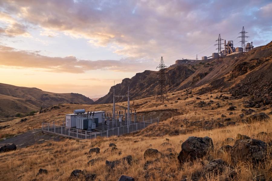Electrical substation and high-voltage pylons running up a mountain slope to a mine processing plant.