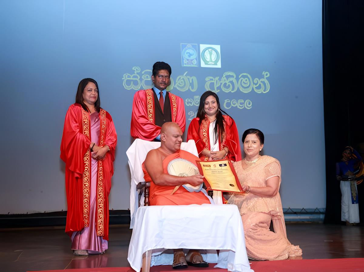 At Swarna Abhiman, Darshani Chandrasena receives a certificate from a seated monk