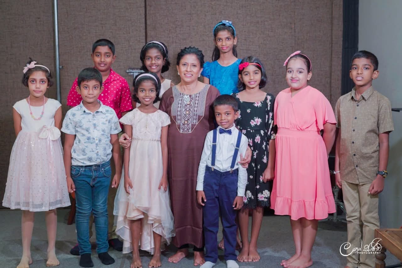 In a maroon kurta, Darshani Chandrasena stands among ten dressed-up young students indoors