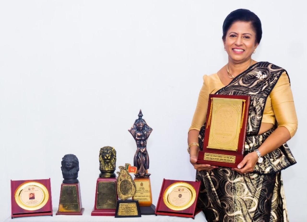 Darshani Chandrasena holds a plaque beside her collection of trophies and awards