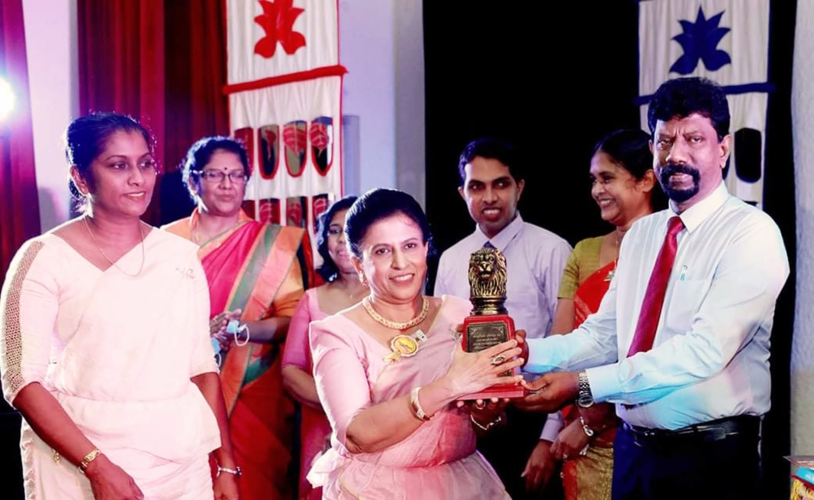 Darshani Chandrasena, in a pink sari, receives a bronze lion trophy