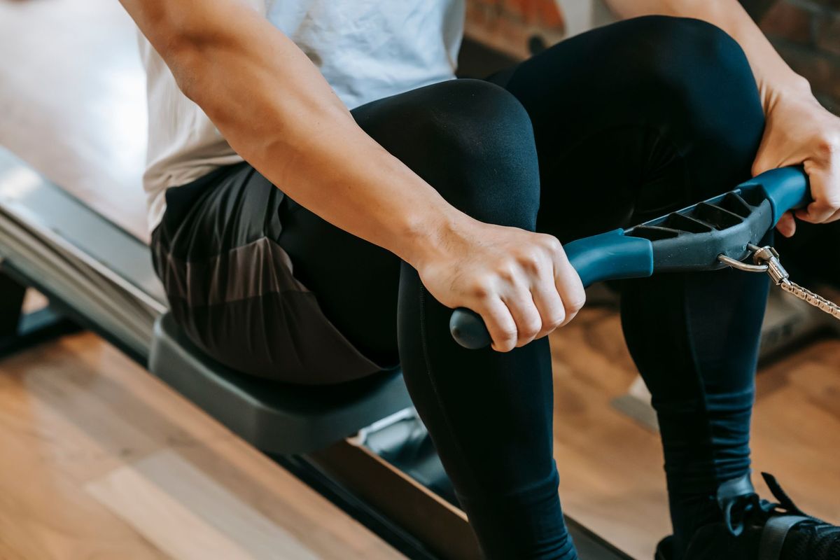 Close-up of a person gripping a rowing machine handle above the sliding seat