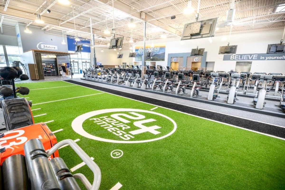 Bright, spacious gym featuring state-of-the-art cardio equipment, functional training area with artificial turf, and inspiring motivational decor, promoting health and fitness goals.