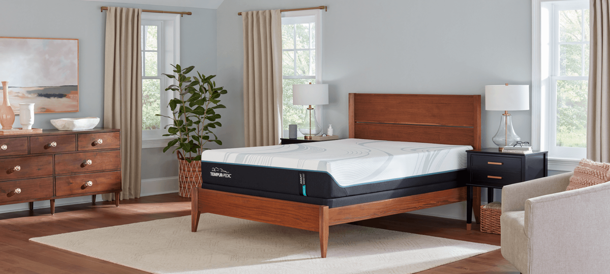 Tempur-Pedic Adapt mattress on a wooden bed frame in a bright bedroom.