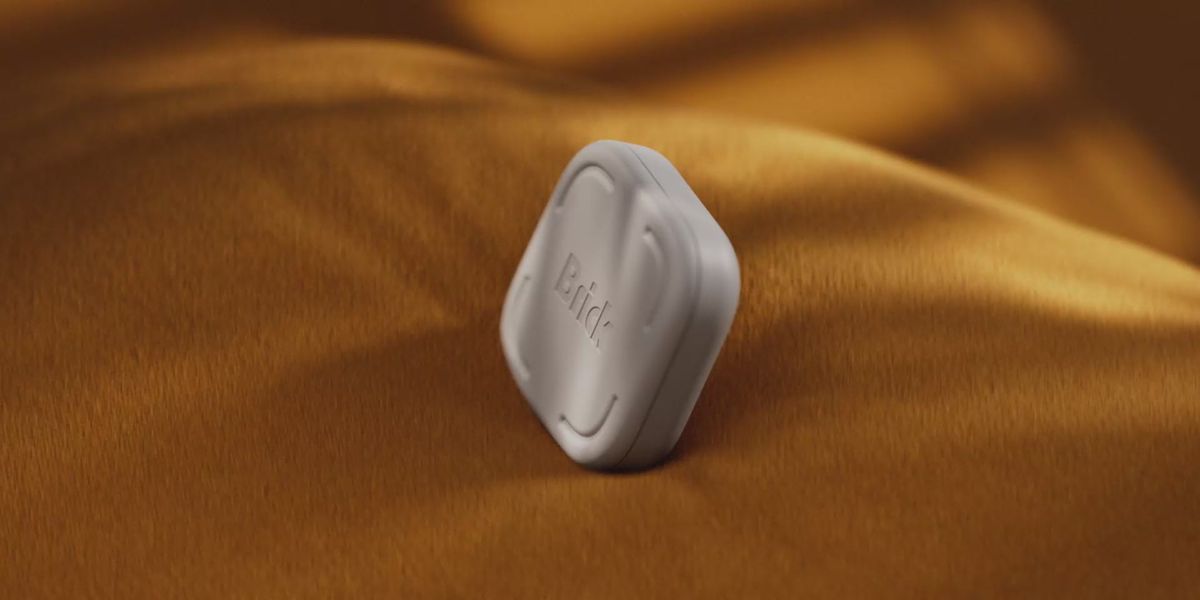 Gray Brick phone-blocking device standing on gold-colored fabric.