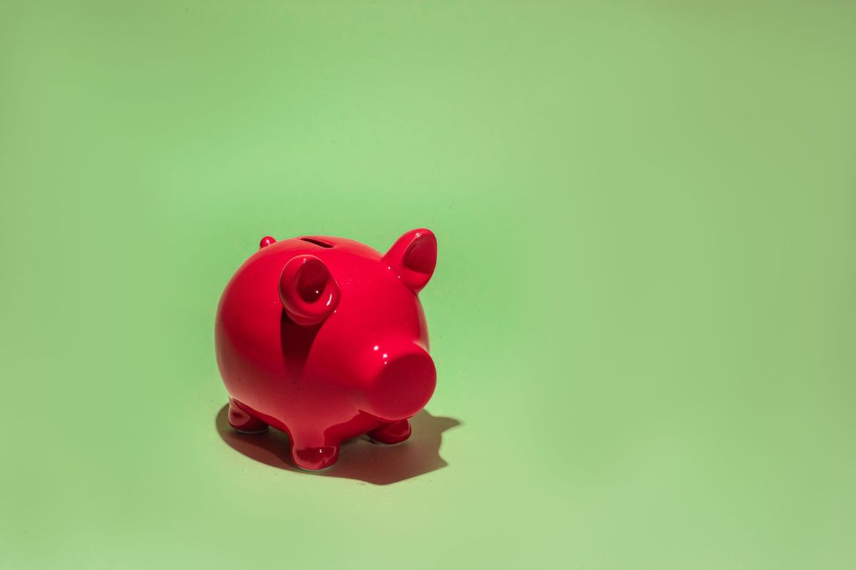 A red piggy bank on a light green background.